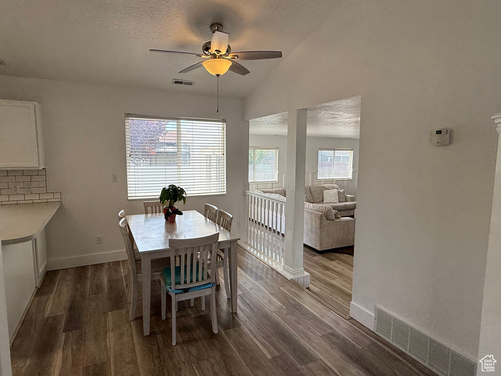 Dining room with ceiling fan, dark wood-type flooring, baseboards, and vaulted ceiling