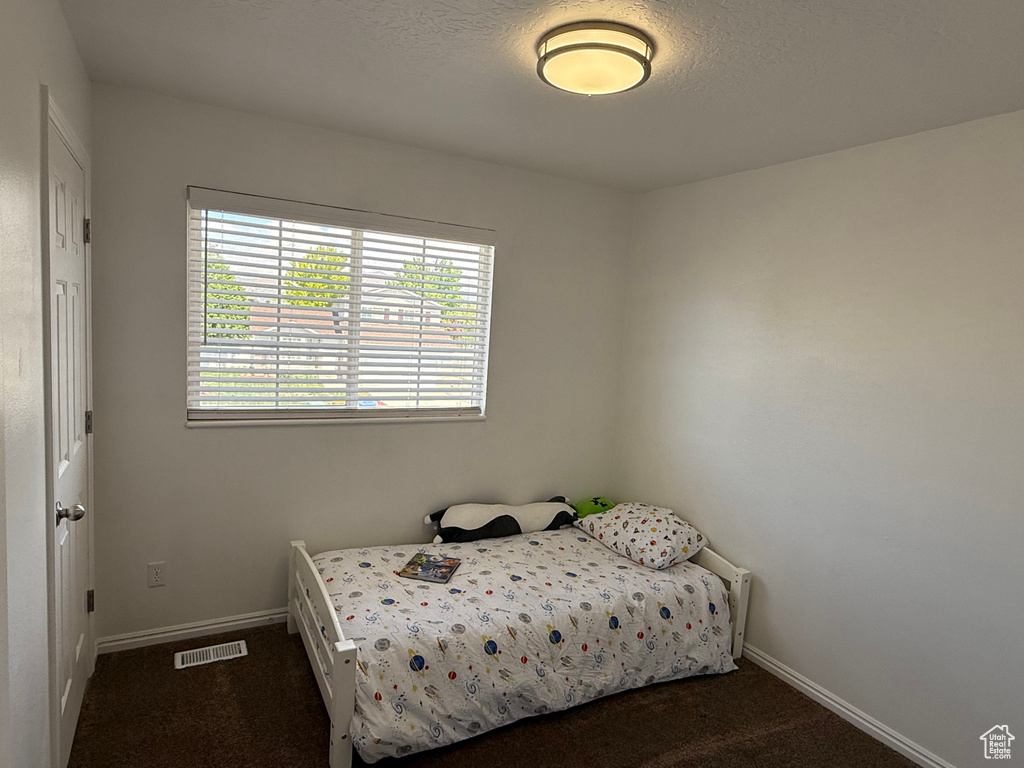 Bedroom featuring dark colored carpet and baseboards