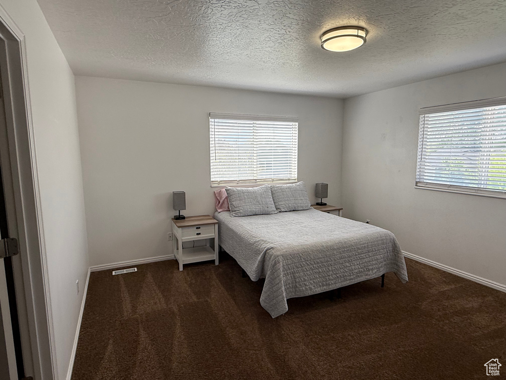 Bedroom with carpet, a textured ceiling, and baseboards