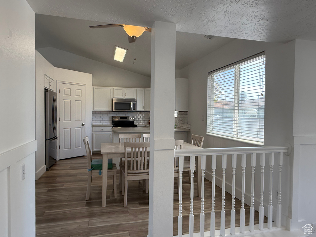 Kitchen featuring stainless steel appliances, ceiling fan, wood finished floors, backsplash, and white cabinets