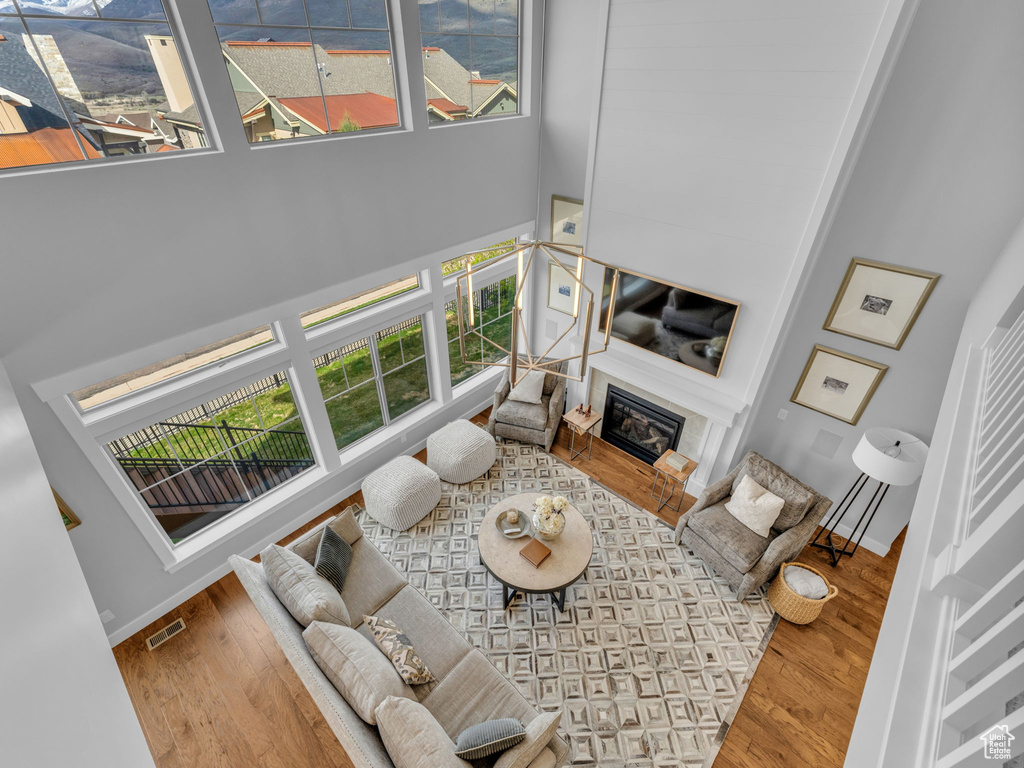Living room featuring a towering ceiling, visible vents, a wealth of natural light, and wood finished floors