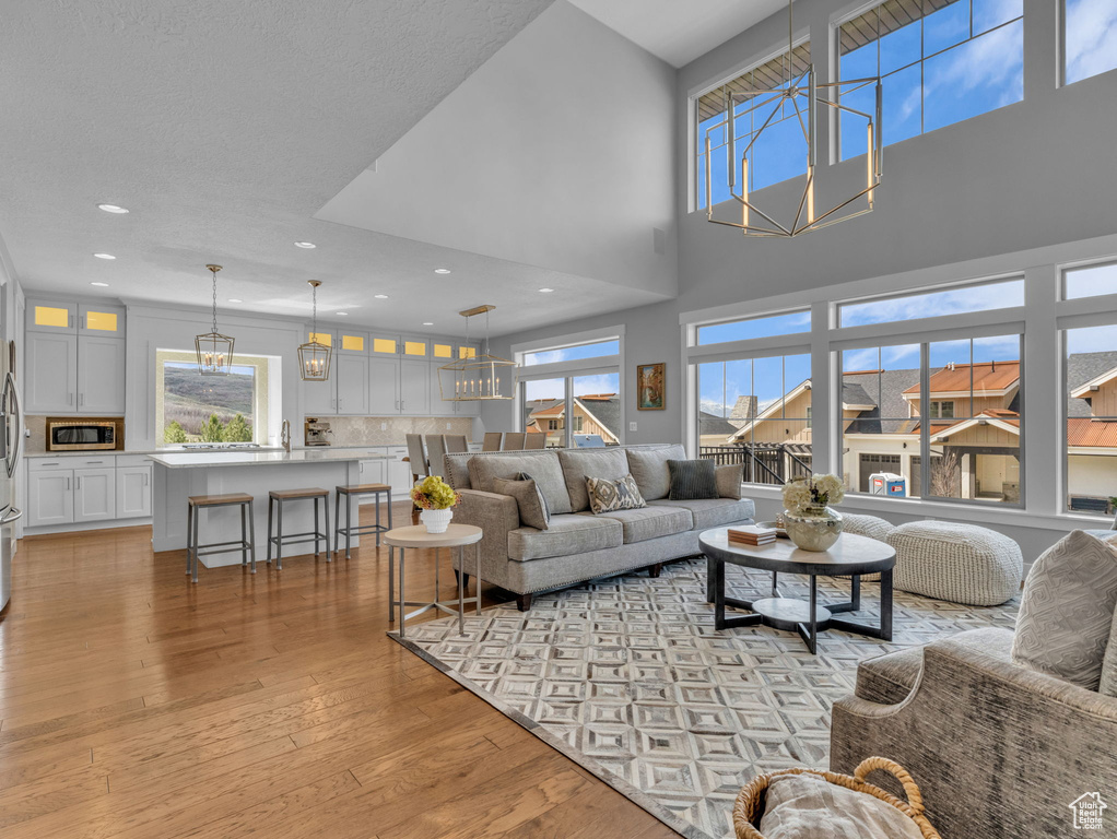 Living room featuring recessed lighting, an inviting chandelier, a high ceiling, and light wood finished floors