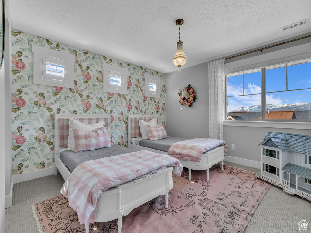 Carpeted bedroom with baseboards, wallpapered walls, visible vents, and a textured ceiling