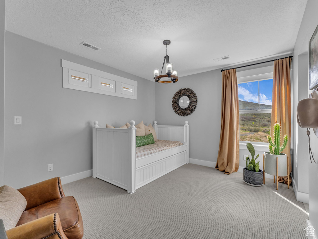 Bedroom with visible vents, baseboards, a notable chandelier, and light carpet