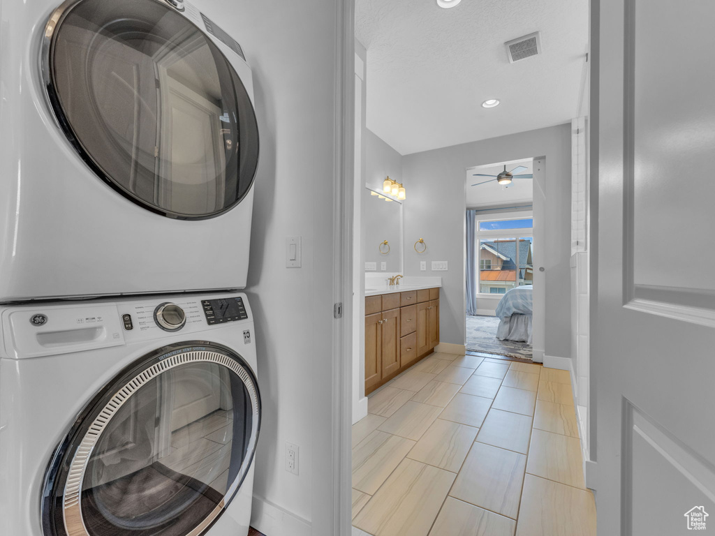 Clothes washing area featuring recessed lighting, stacked washer and clothes dryer, a ceiling fan, visible vents, and baseboards