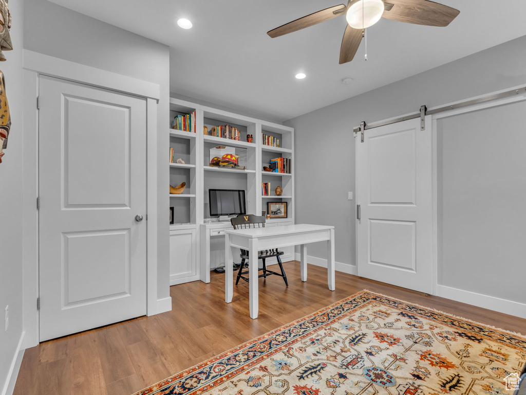 Home office with ceiling fan, a barn door, baseboards, light wood-type flooring, and recessed lighting