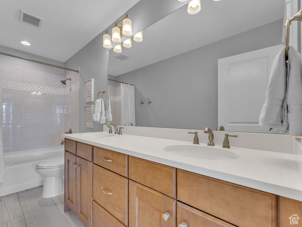 Bathroom featuring toilet, double vanity, a sink, and visible vents