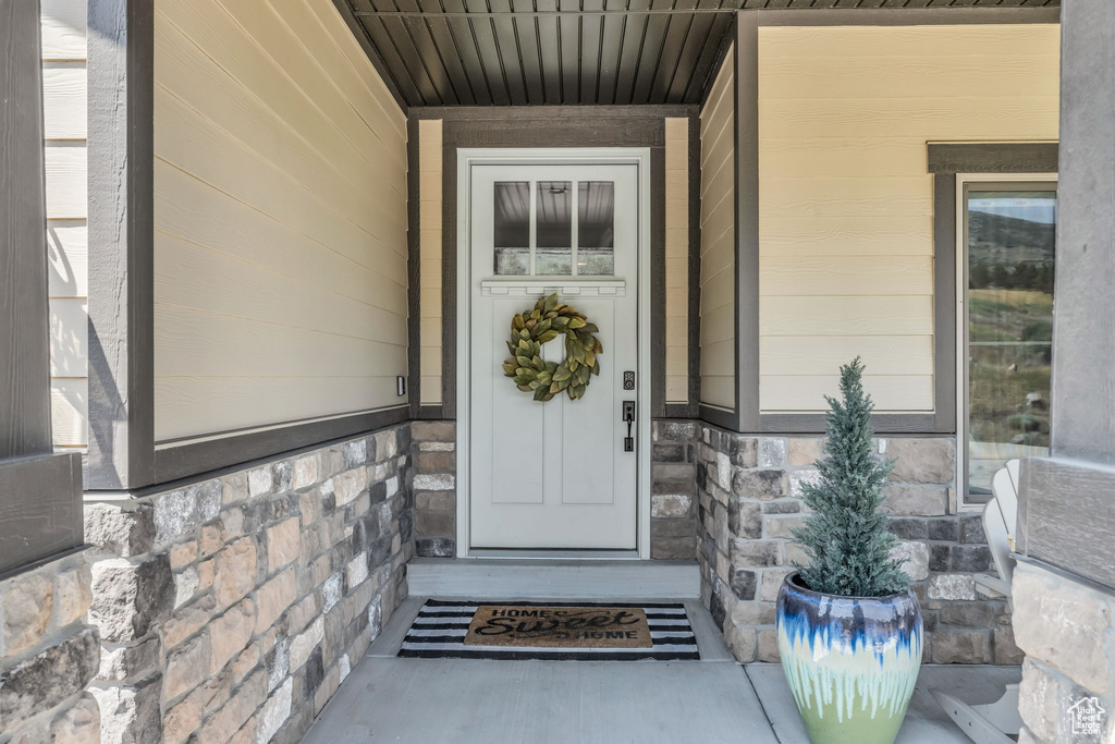 View of exterior entry featuring a porch and stone siding