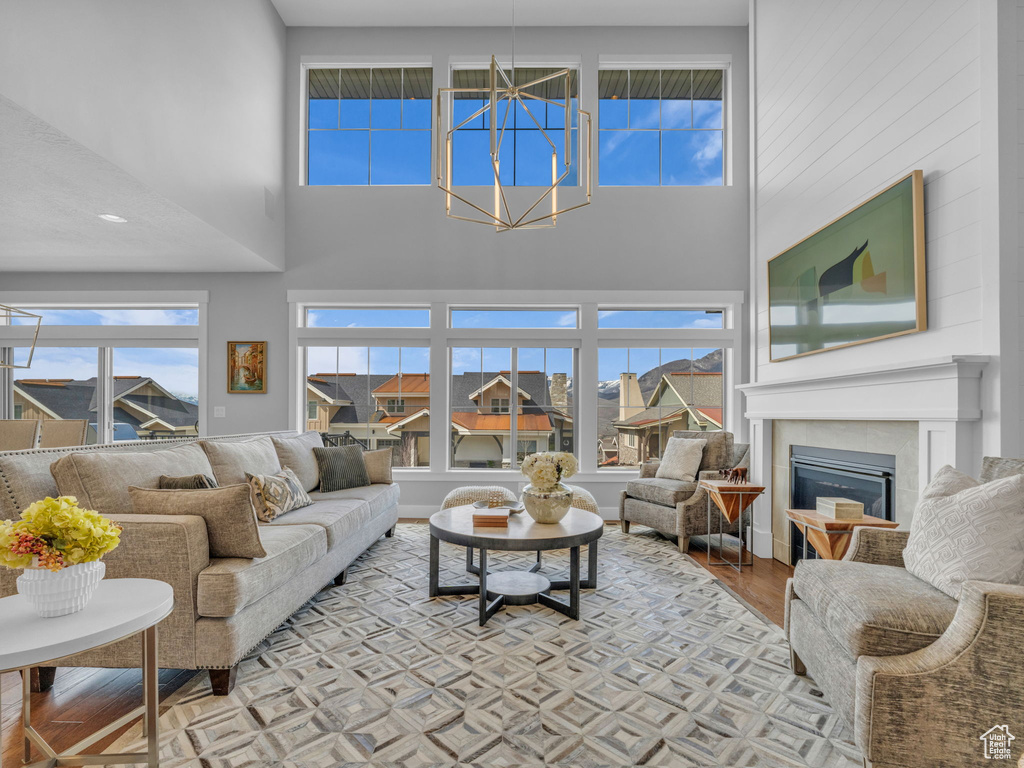Living room with a towering ceiling, a glass covered fireplace, a notable chandelier, and light wood-style flooring