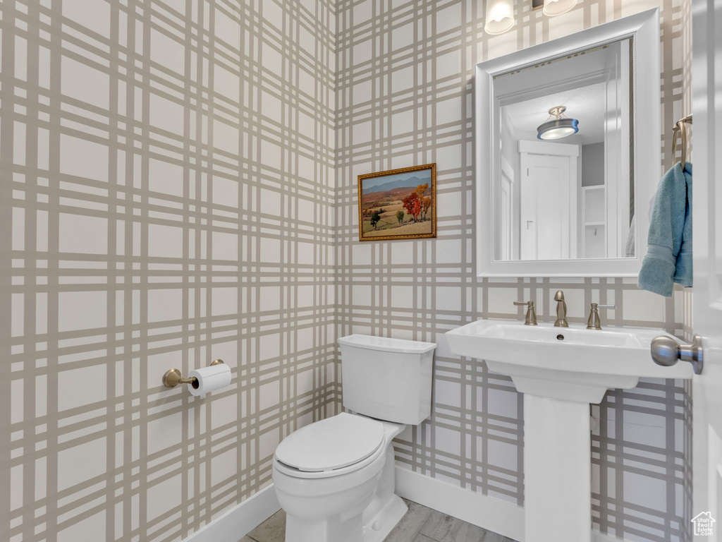 Half bathroom featuring wallpapered walls and toilet
