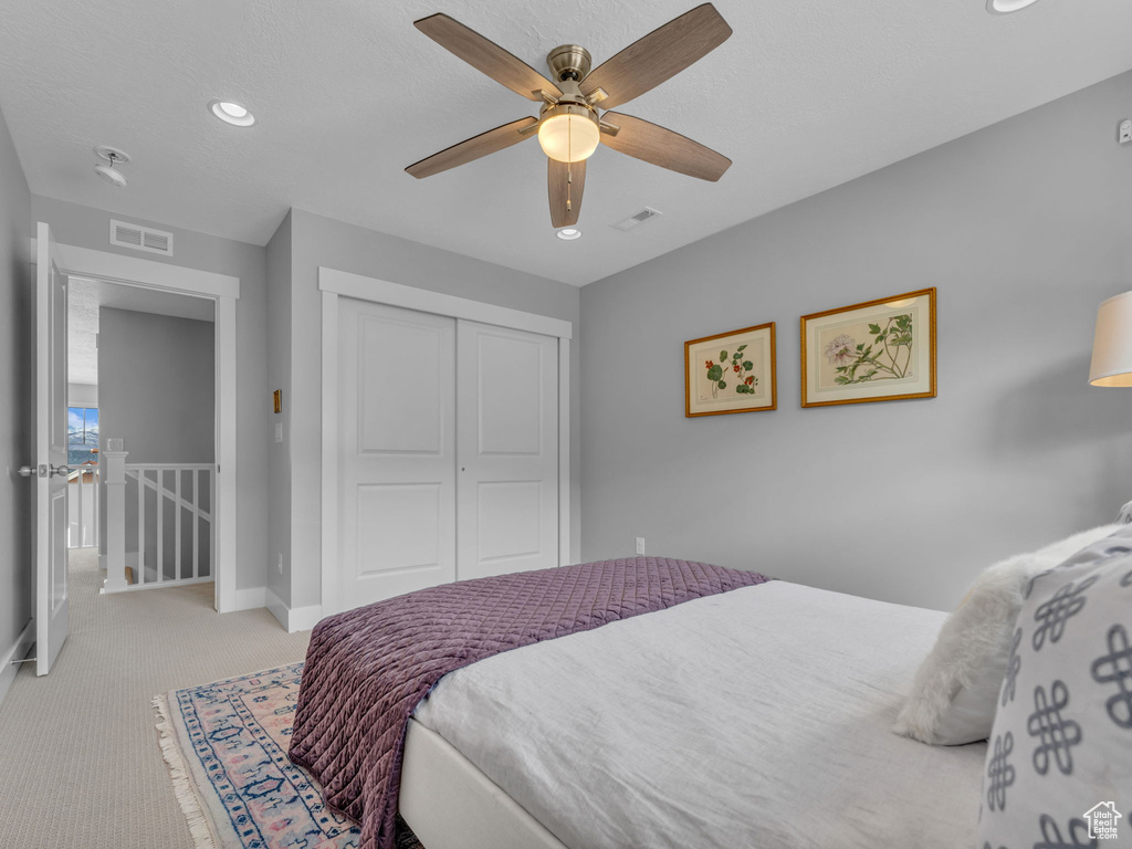 Bedroom featuring visible vents, a closet, baseboards, and light carpet