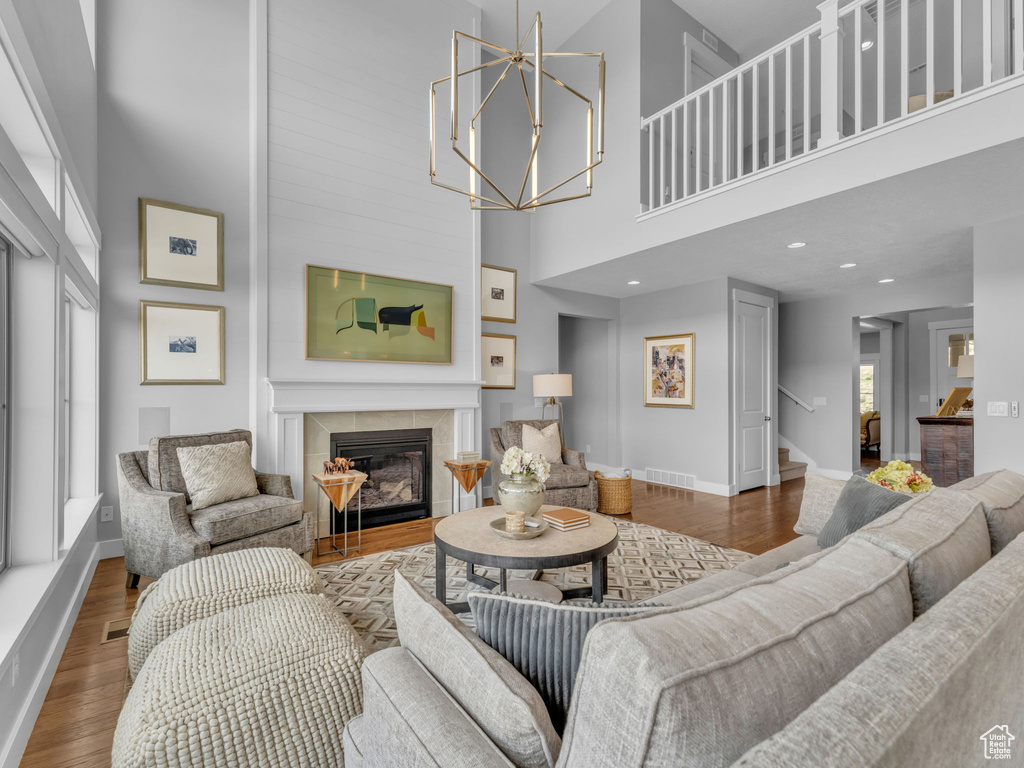 Living room featuring visible vents, baseboards, a fireplace, a towering ceiling, and wood finished floors