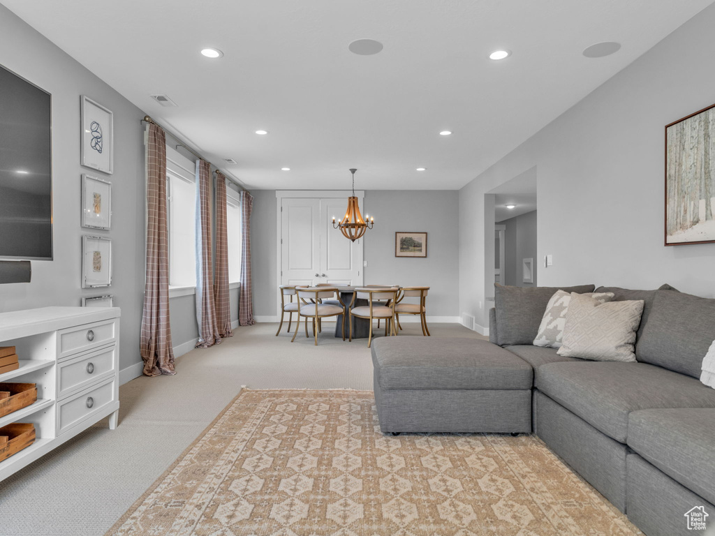 Living area with light colored carpet, recessed lighting, a notable chandelier, and baseboards