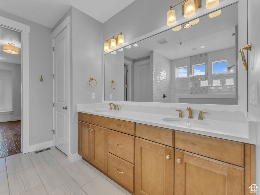 Full bathroom with baseboards, visible vents, double vanity, and a sink