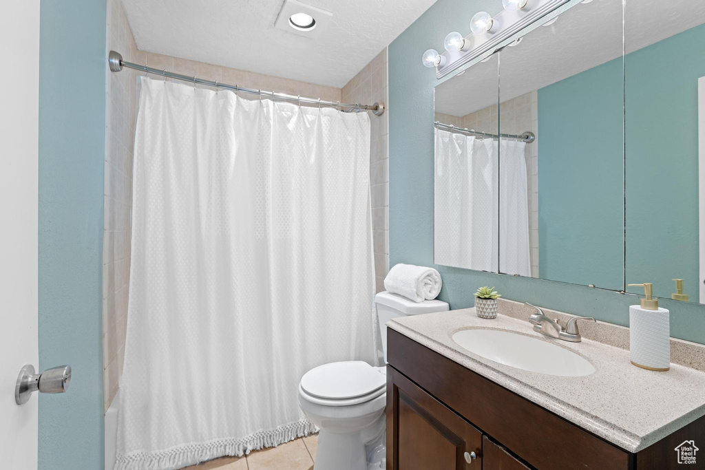 Bathroom featuring toilet, tile patterned flooring, vanity, and shower / bath combo with shower curtain