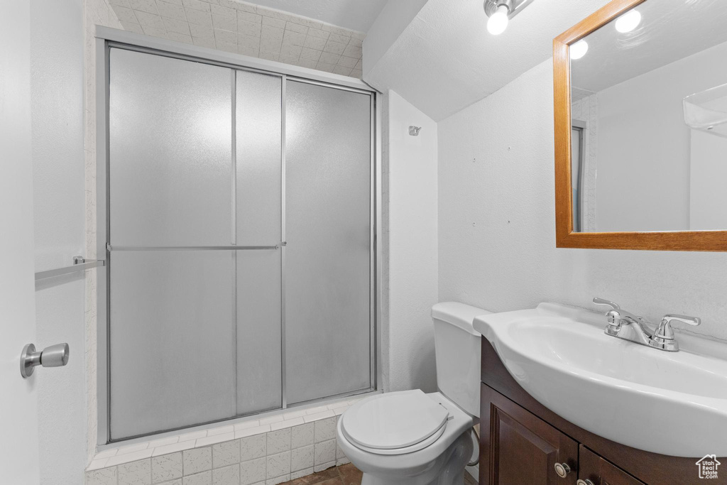 Full bath featuring a shower with shower door, toilet, and vanity