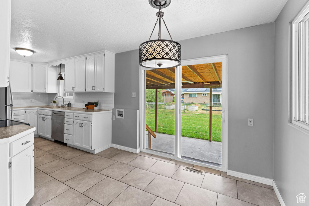 Kitchen featuring appliances with stainless steel finishes, white cabinets, backsplash, baseboards, and a textured ceiling