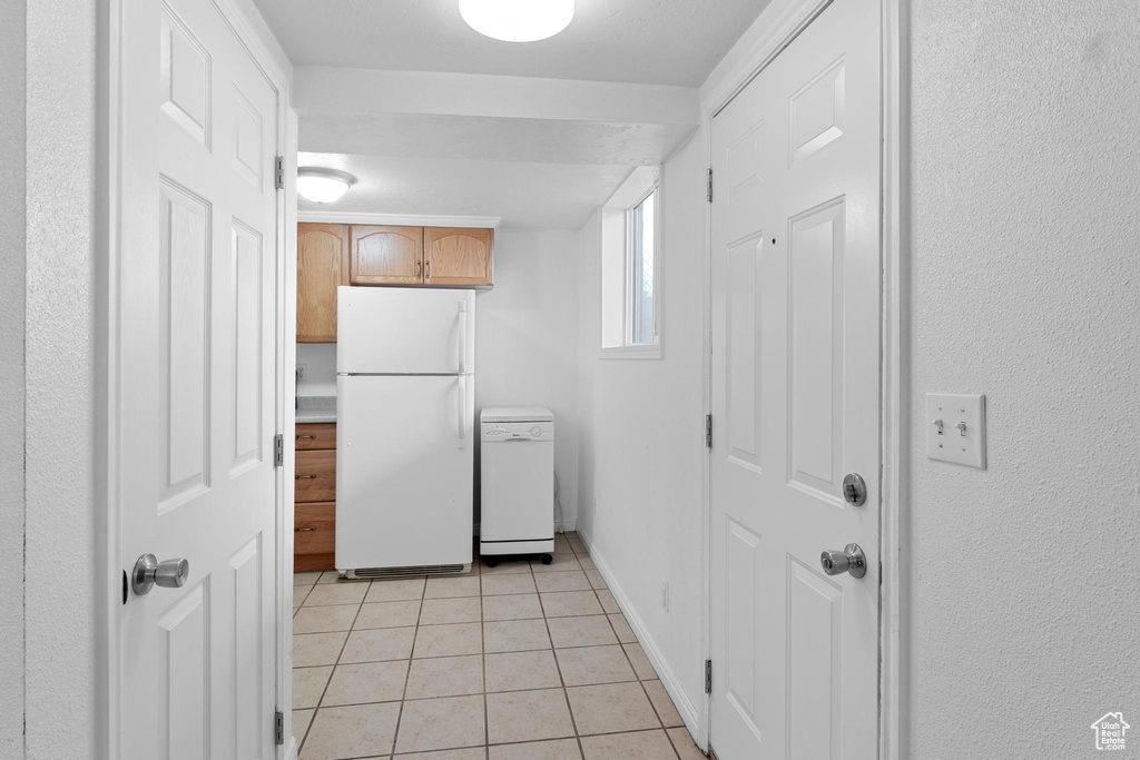 Kitchen featuring freestanding refrigerator, light tile patterned floors, light countertops, and baseboards