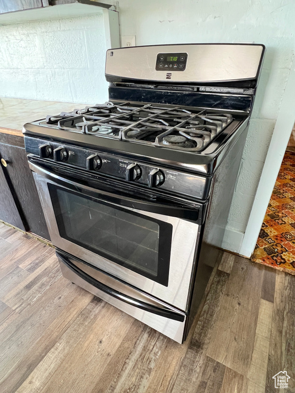 Kitchen view of stainless steel range with gas stovetop, wood finished floors, and light countertops