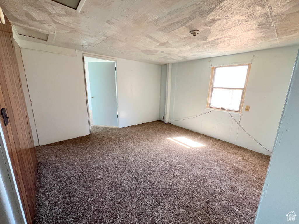 Empty room with attic access and carpet flooring