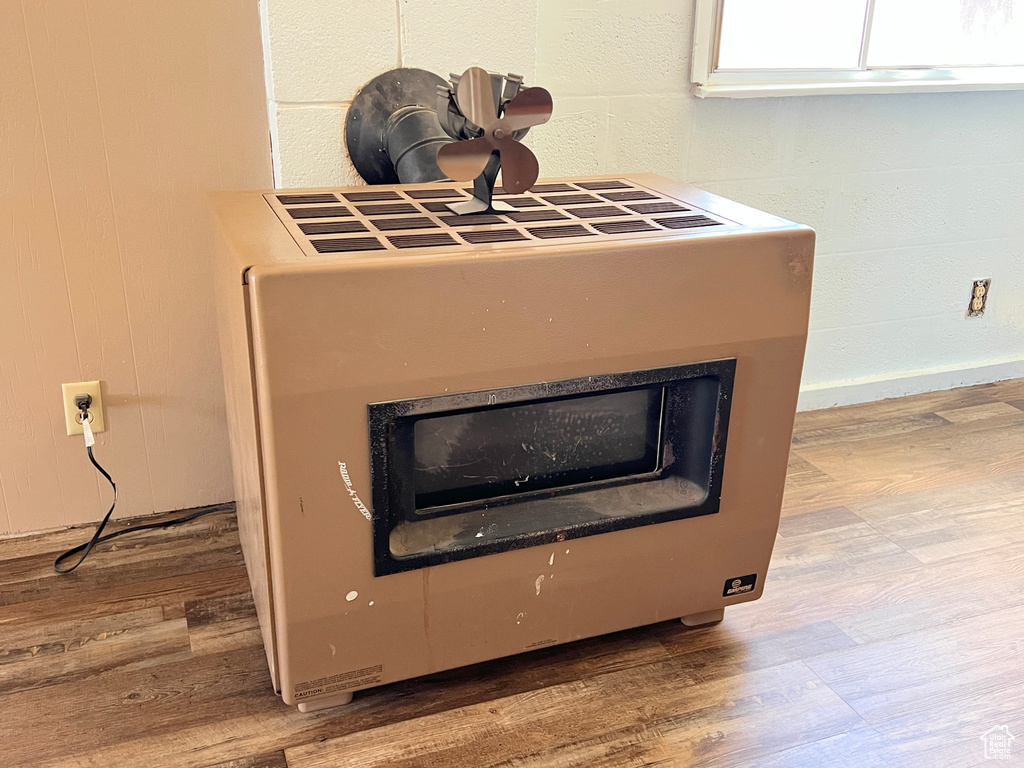 Detailed view of heating unit, wood finished floors, and a fireplace