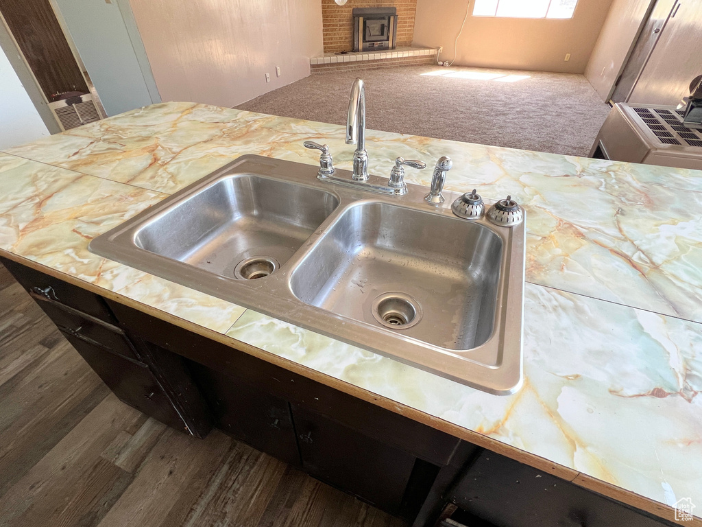 Kitchen view of a sink, wood finished floors, a fireplace, and light countertops
