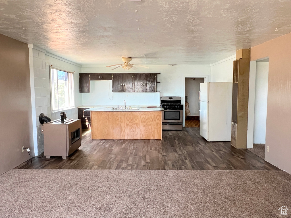 Kitchen with stainless steel gas range, freestanding refrigerator, a sink, a ceiling fan, and light countertops