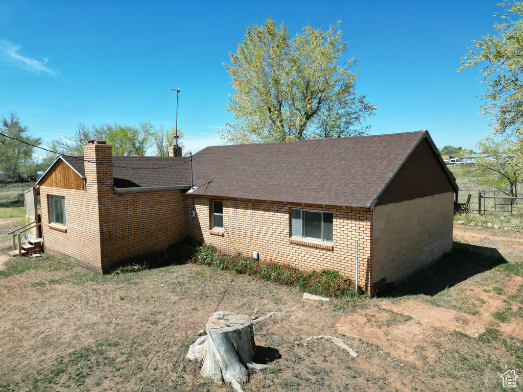 View of side of property with roof with shingles, brick siding, and a chimney