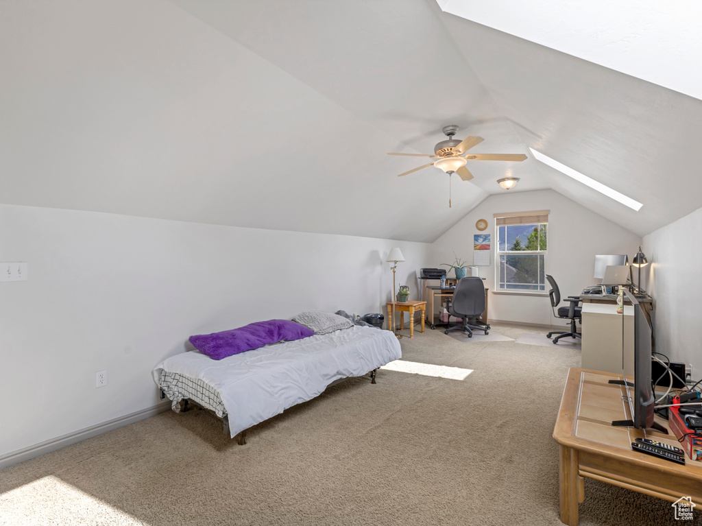 Bedroom with a skylight, lofted ceiling, carpet floors, a desk, and baseboards