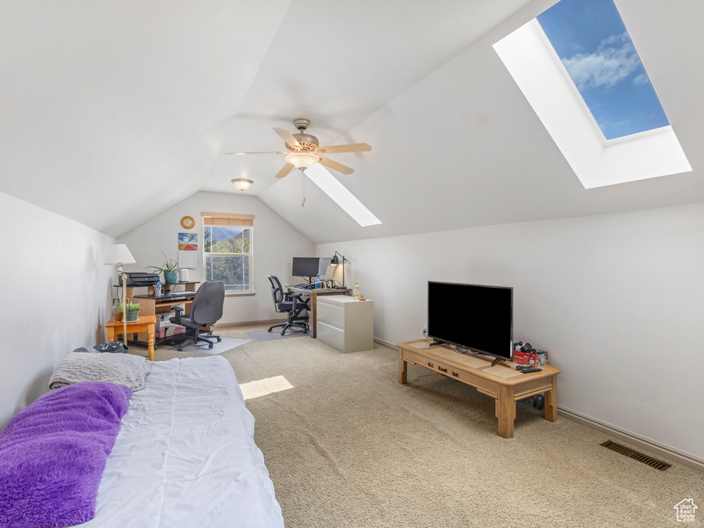 Bedroom featuring a skylight, carpet floors, lofted ceiling, an office area, and a ceiling fan