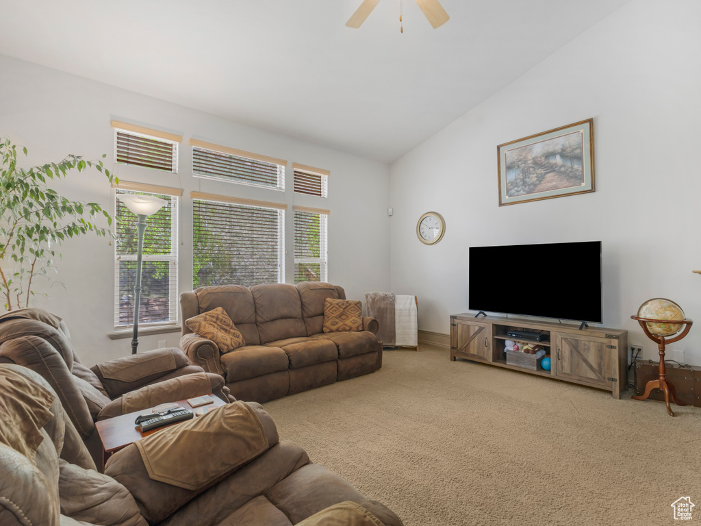 Carpeted living room with ceiling fan and lofted ceiling