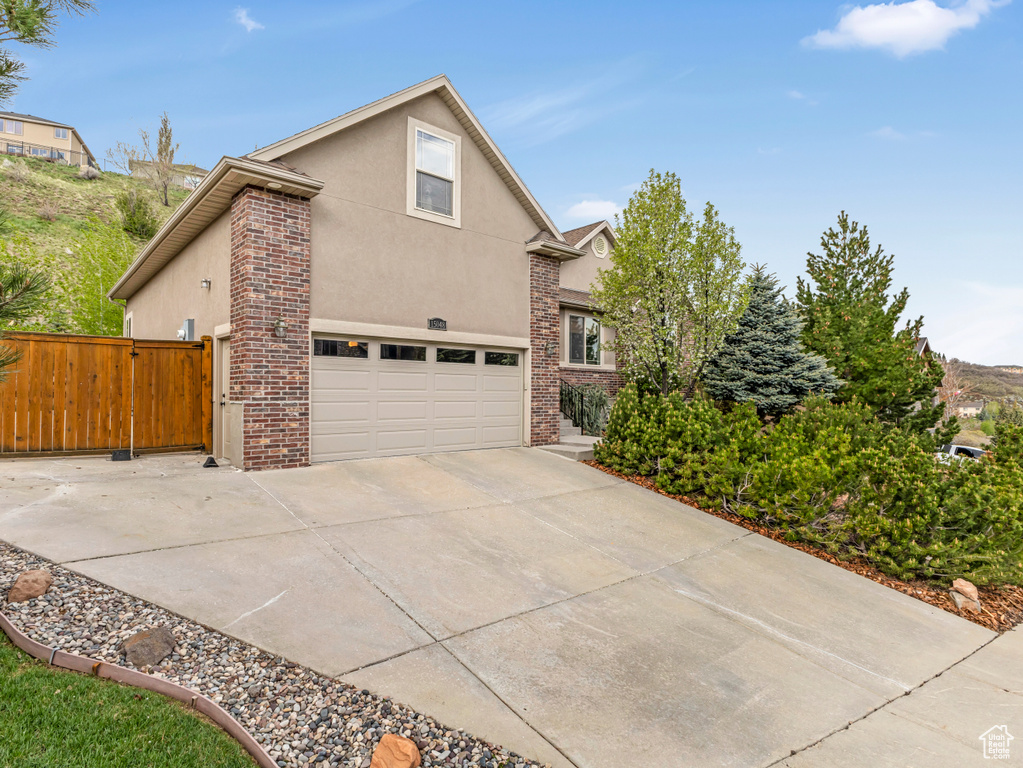 View of home\\\'s exterior featuring stucco siding, concrete driveway, fence, and brick siding