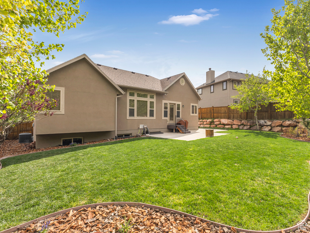 Rear view of property featuring a patio area, central AC unit, entry steps, stucco siding, and a shingled roof