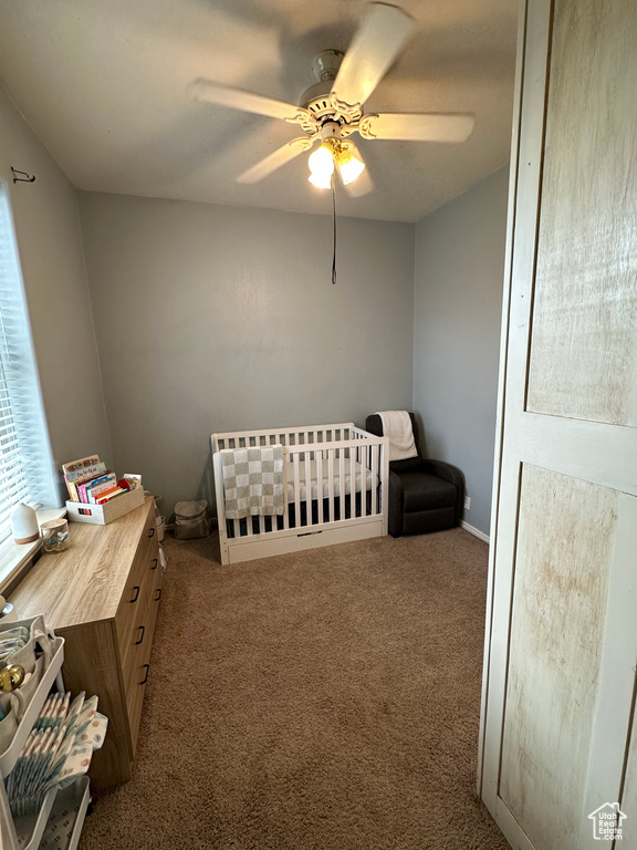 Bedroom featuring carpet flooring, a nursery area, and a ceiling fan