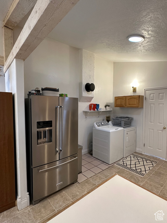 Laundry room with washing machine and clothes dryer, light tile patterned floors, a textured ceiling, and baseboards