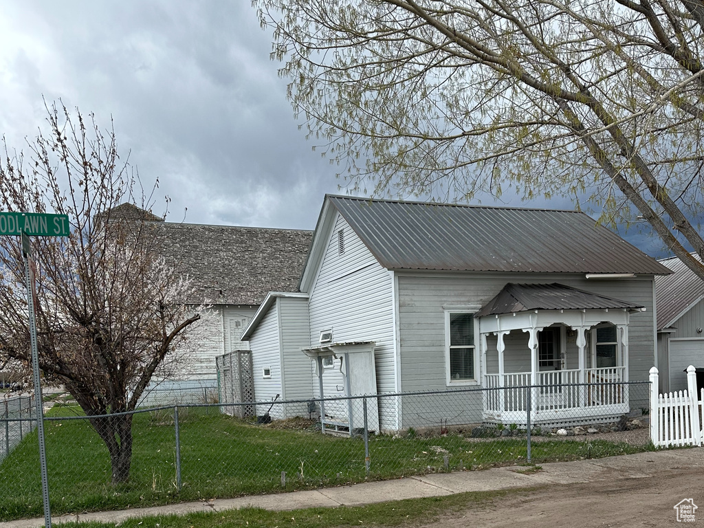 View of front of property with a fenced front yard, a porch, and metal roof