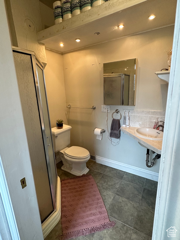 Bathroom with a shower stall, toilet, a sink, tile patterned flooring, and baseboards
