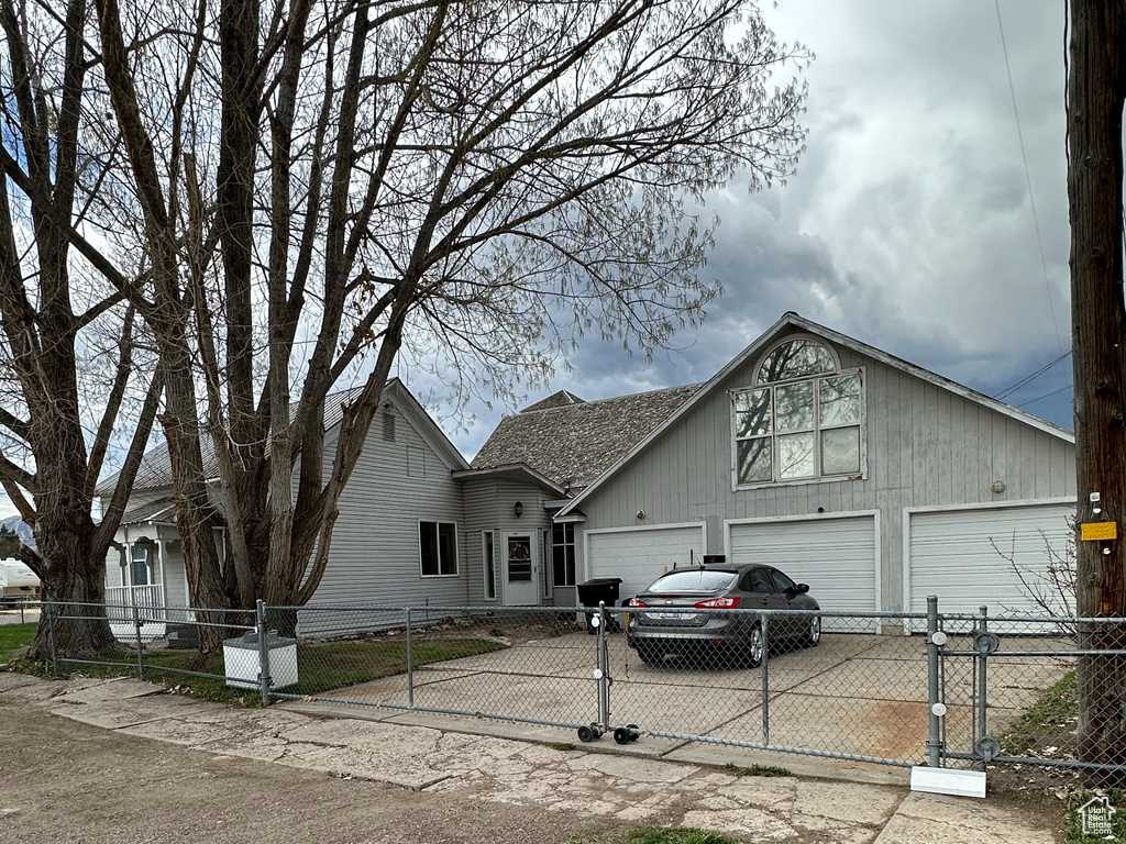 View of front facade featuring driveway, a fenced front yard, an attached garage, and a gate