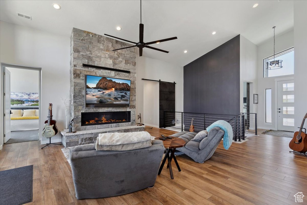 Living area featuring high vaulted ceiling, a stone fireplace, a ceiling fan, wood finished floors, and recessed lighting
