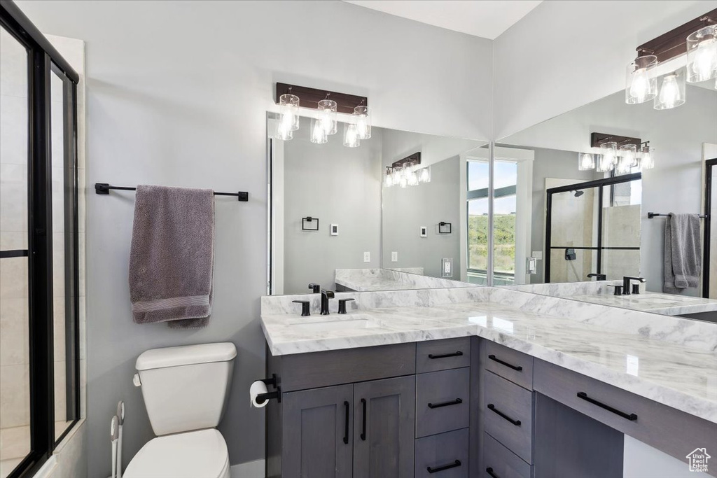 Bathroom with toilet, a shower with door, and double vanity