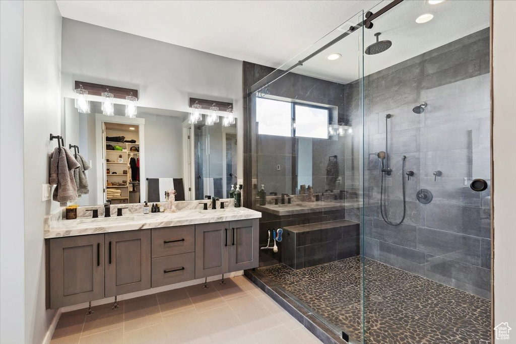 Full bath featuring a stall shower, double vanity, a spacious closet, tile patterned floors, and recessed lighting