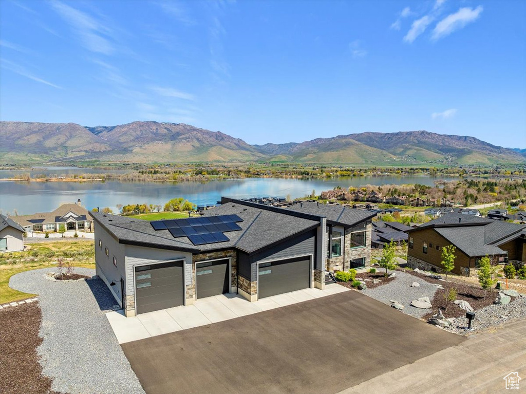 View of front of house featuring a garage, concrete driveway, a water and mountain view, and stone siding