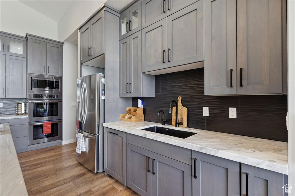 Kitchen with stainless steel appliances, a sink, gray cabinets, and decorative backsplash