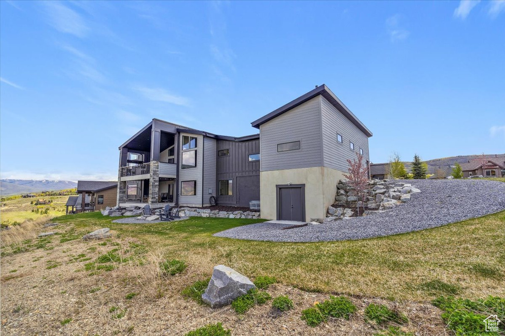 Back of house with a balcony, a lawn, and a patio area