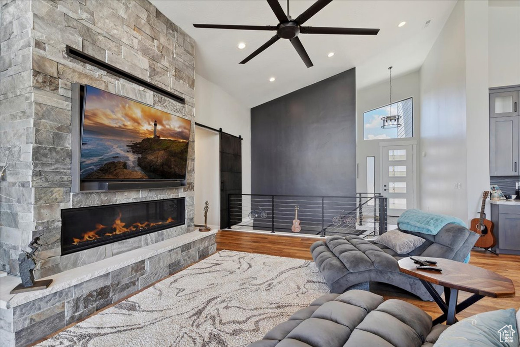 Living area with a high ceiling, wood finished floors, a fireplace, recessed lighting, and ceiling fan