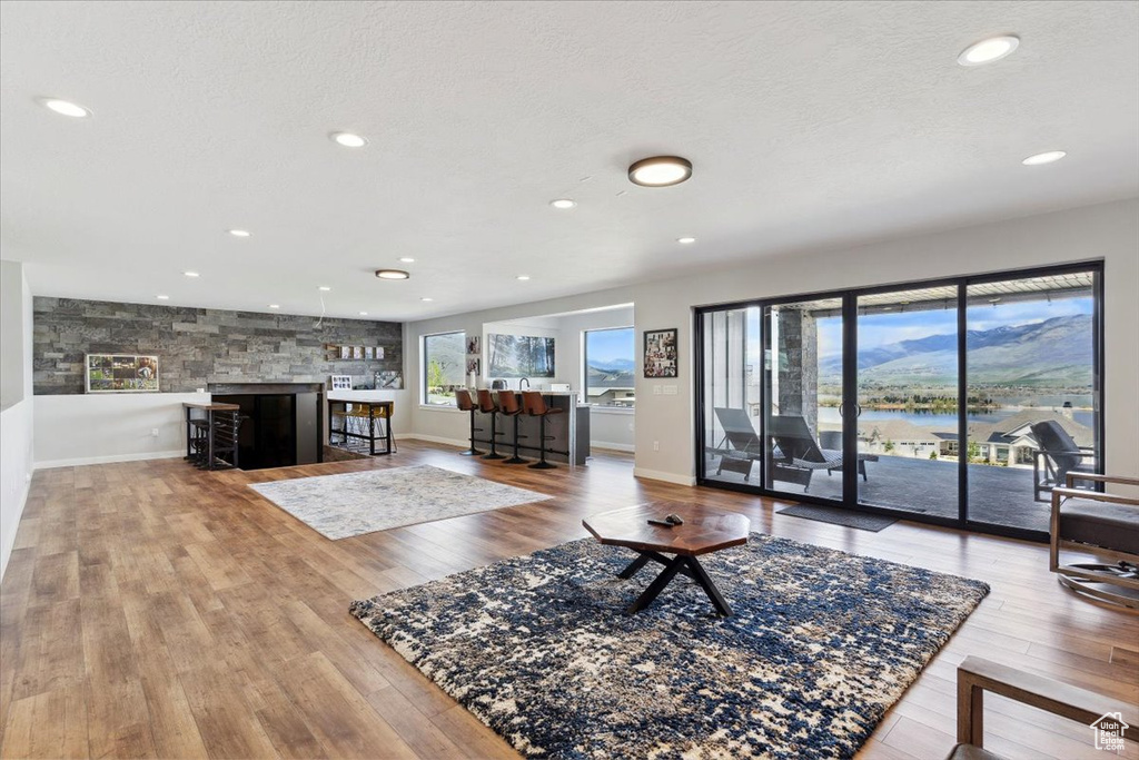 Living area with wood finished floors, recessed lighting, a textured ceiling, a water view, and baseboards