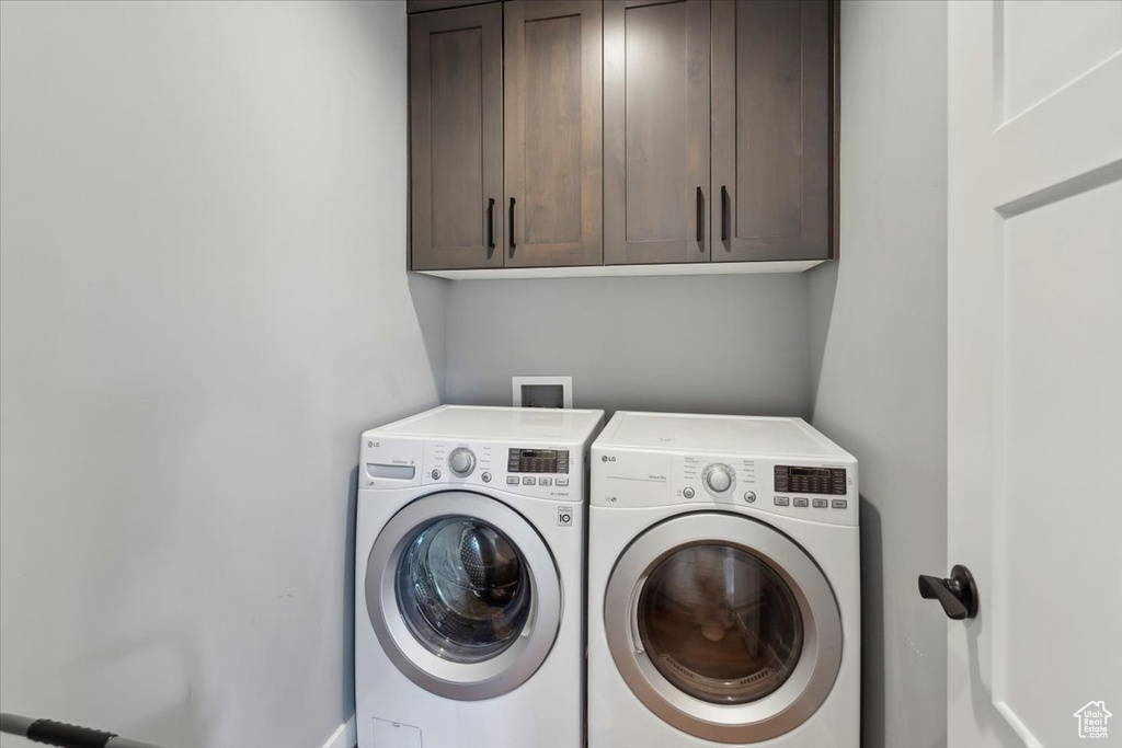 Clothes washing area featuring cabinet space and separate washer and dryer