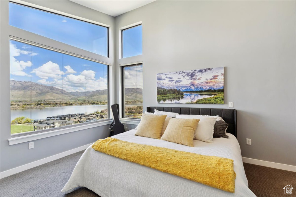 Carpeted bedroom featuring multiple windows, a water and mountain view, and baseboards