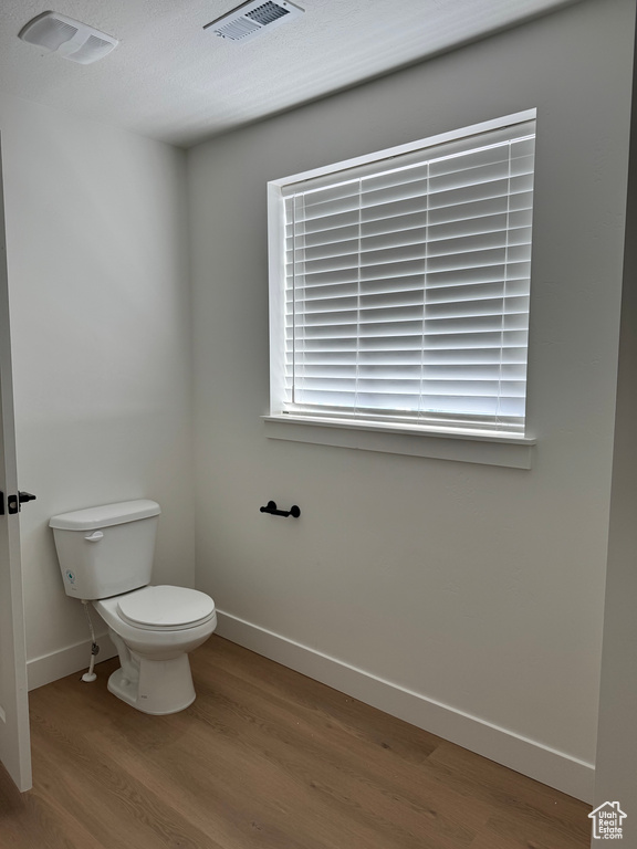 Bathroom featuring wood finished floors, toilet, and baseboards