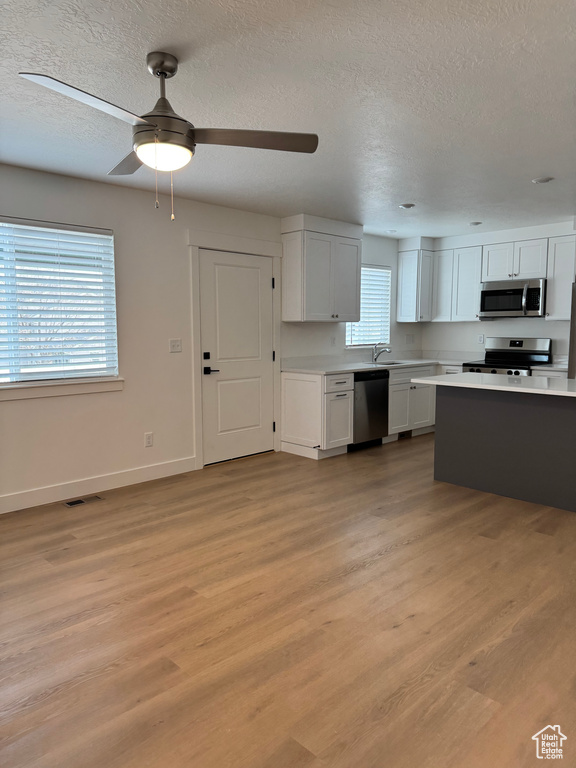 Kitchen with appliances with stainless steel finishes, a sink, light countertops, baseboards, and a textured ceiling